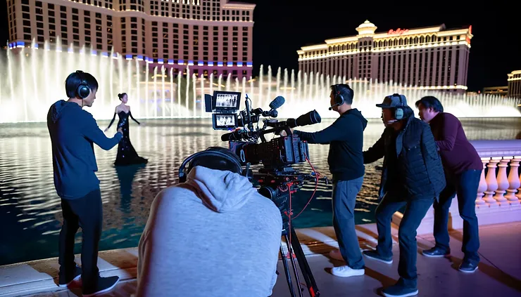 A professional video crew filming at night in front of Bellagio fountains