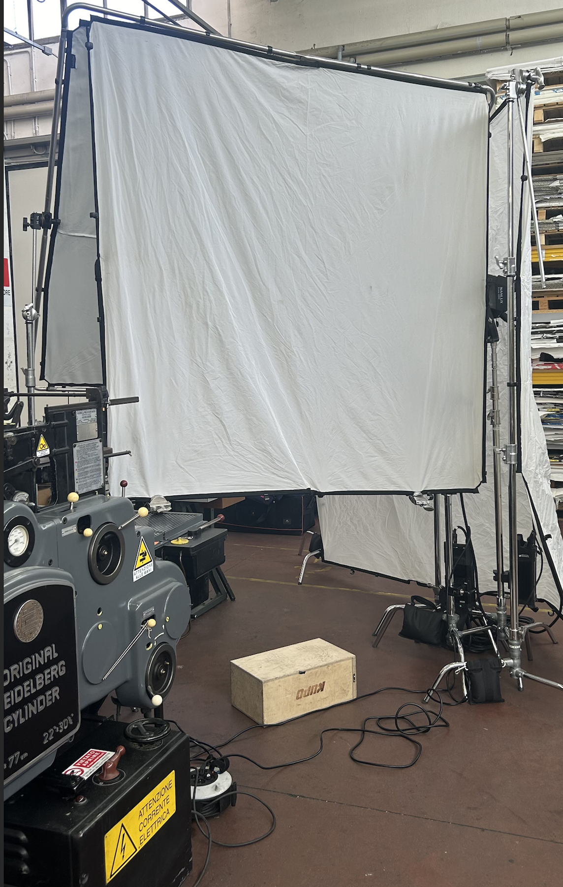 example of a book lighting setup in an industrial setting with c-stands, diffusion, an apple box and other equipment