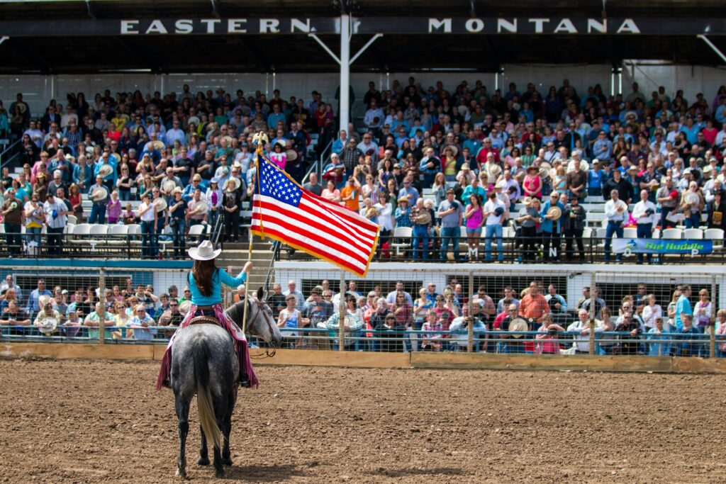 A cowgirl carrying the USA flag while riding a horse in the NRF