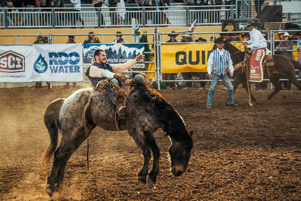 A cowboy balancing his weight while riding a horse