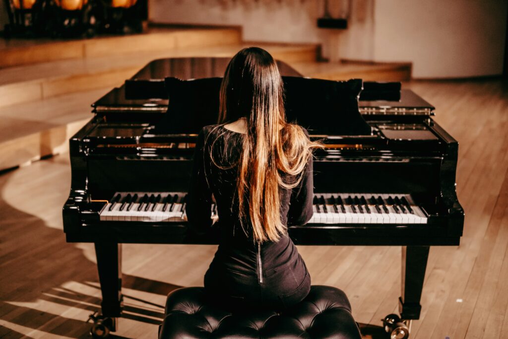 A woman playing the piano facing the back of the camera for vdeo production