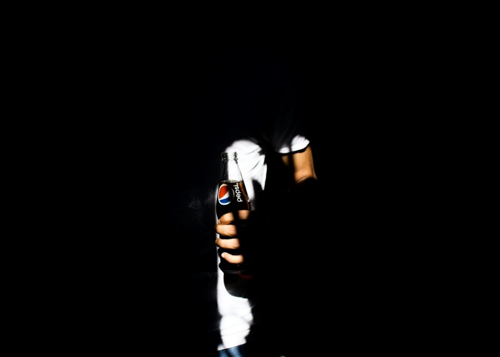 A man in the dark holding Pepsi